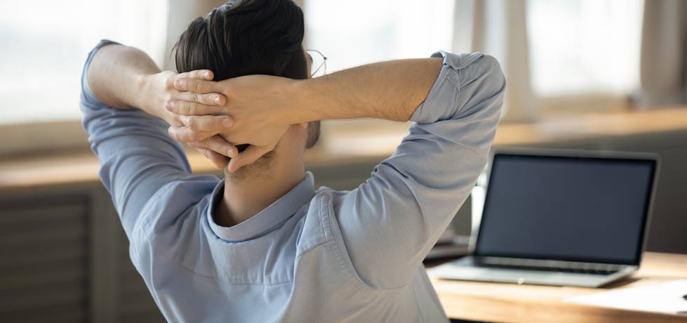 Homem com as mãos atrás da cabeça no trabalho