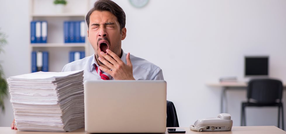 Homem bocejando no trabalho- desmotivação no trabalho