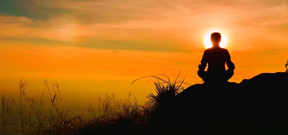 Homem meditando no pôr do sol