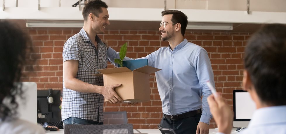 Homem segurando caixa de papelão com pertences nas mãos no primeiro dia de emprego