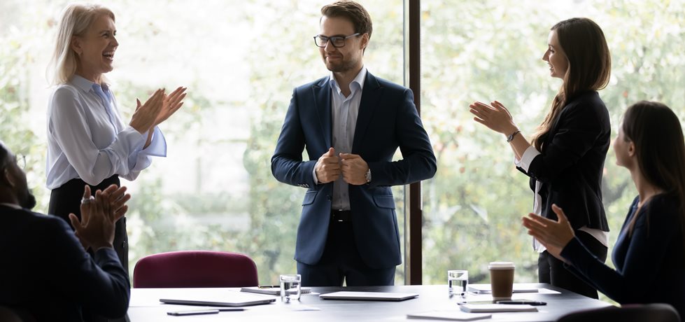 Homem recebendo parabéns da equipe após ser promovido